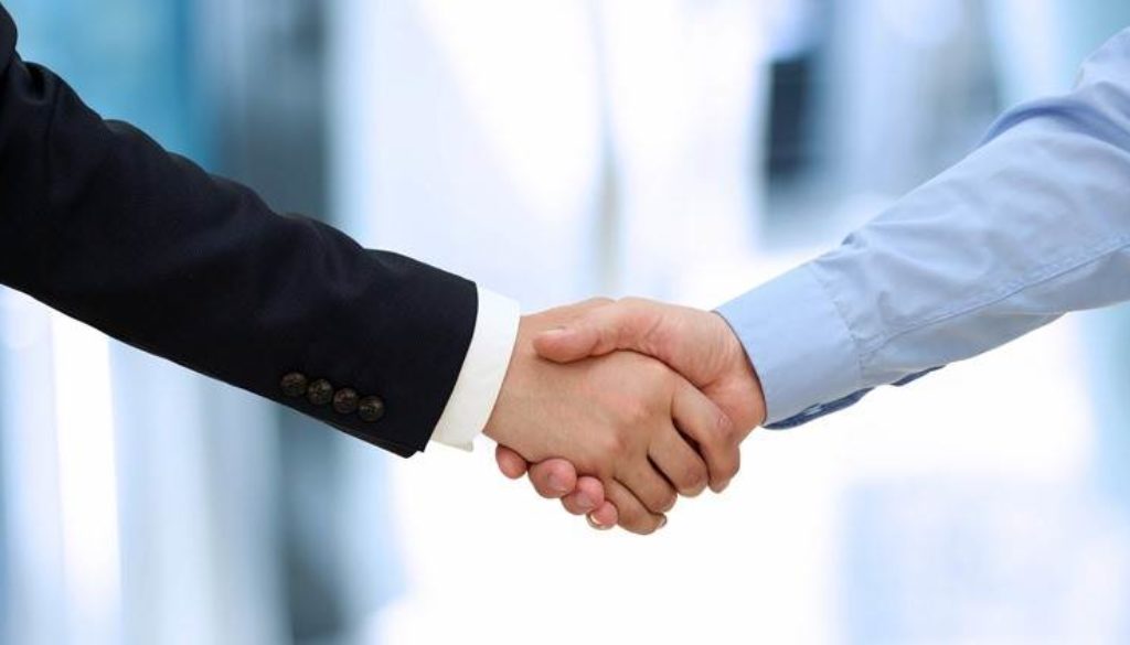 Image of a firm handshake  between two colleagues in office.